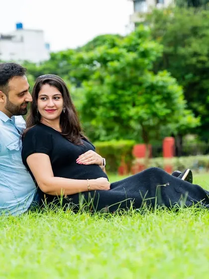 A relaxed moment on the grass. This couple enjoys a peaceful time together in the park, a simple and sweet memory of their pregnancy.