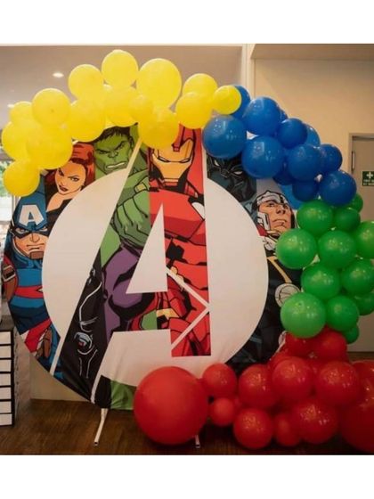 A circular backdrop with the iconic Avengers logo, framed by a balloon arch in the colors of the main heroes.