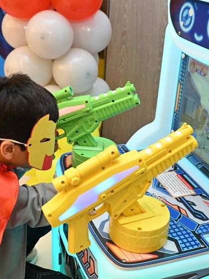 A little hero wearing an Iron Man mask gets serious at the shooting arcade game. I make sure to include a variety of games that appeal to different age groups and interests.