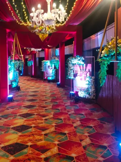 A colorful and vibrant entrance walkway at Ellora Banquet hall. The geometric-patterned carpet, hanging floral baskets, and red drapes create a festive and energetic vibe.