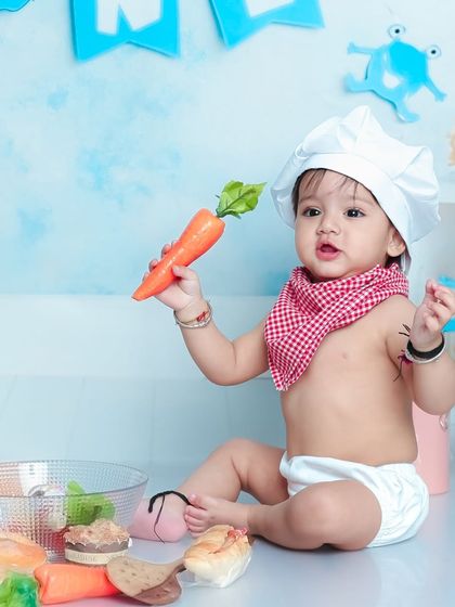 This little chef is presenting a fresh carrot, an essential ingredient. The simple costume with a chef's hat and bandana is absolutely adorable.