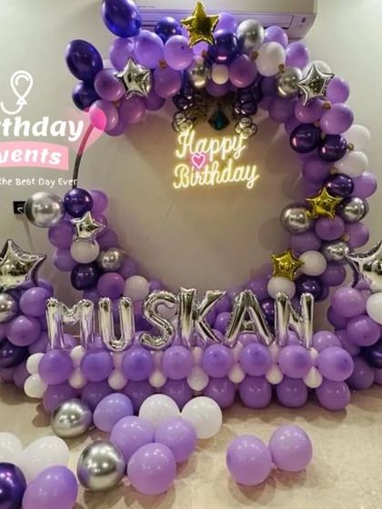 A vibrant purple and silver balloon ring, personalized with the name "MUSKAN" in large silver foil balloons for a truly custom look.