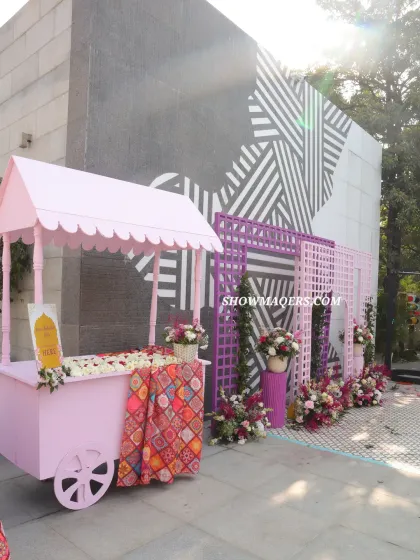 A whimsical pink cart serves as a decorative element and photo op at this pink-themed Haldi, adorned with flowers and traditional fabrics.