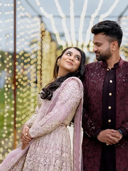 A happy couple enjoying their Sangeet night against a backdrop of cascading fairy lights. This simple yet elegant decor creates a romantic and magical atmosphere perfect for evening celebrations.
