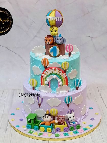 A remarkable 5kg black forest cake with a jungle safari and hot air balloon theme. This two-tier cake features a train with animals at the base and a hot air balloon on top.