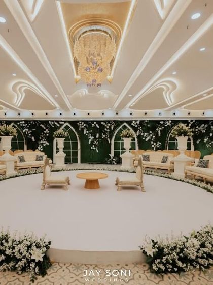 A straight-on view of the circular indoor mandap, emphasizing its symmetry and the clean, sophisticated aesthetic created by the white color palette and lush florals.