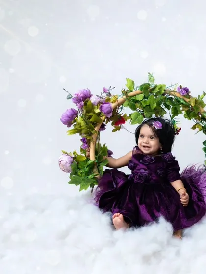 A dreamy portrait of a baby girl on a floral swing, surrounded by soft clouds. This magical setup is perfect for celebrating any milestone, like a half-birthday.