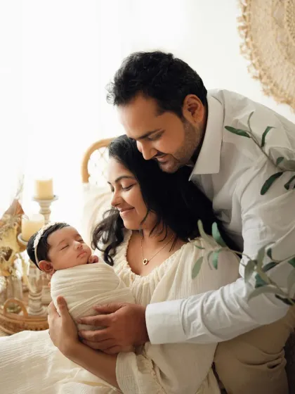 A beautiful family portrait where the parents are looking lovingly at their newborn baby. This shot captures the beginning of their new life as a family.