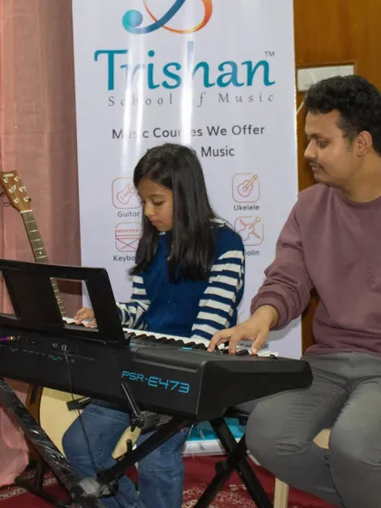 A teacher assists a student during a keyboard performance at the Sarjapur open mic.