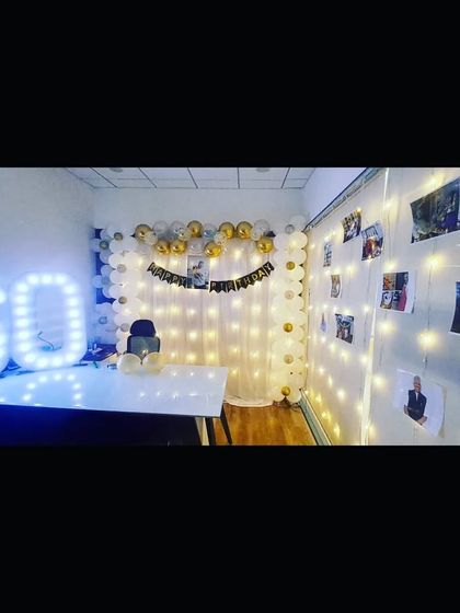 A 60th birthday celebration setup in an office, featuring light-up marquee numbers and a photo wall to cherish old memories.