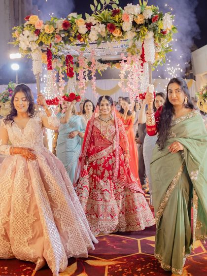 The bride's grand entrance at her reception. She looks absolutely breathtaking under the floral canopy, with her makeup and hair perfectly styled to last through the night of celebrations.