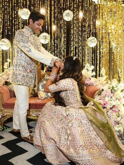 A candid moment on the shimmering gold engagement stage. The sparkling backdrop and soft floral arrangements create a beautiful setting for the couple's special moments.