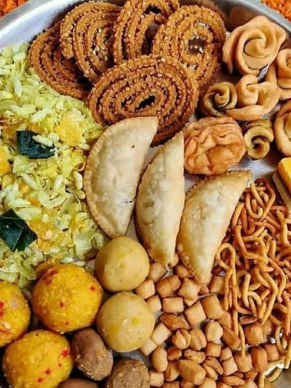 A festive platter of assorted desi snacks. This plate includes chakli, gujiya, laddoos, sev, and other traditional homemade treats perfect for celebrations.