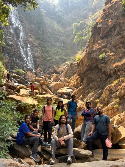 The group poses for a photo on the rocky terrain leading to a waterfall, showcasing the challenging yet rewarding nature of our treks.