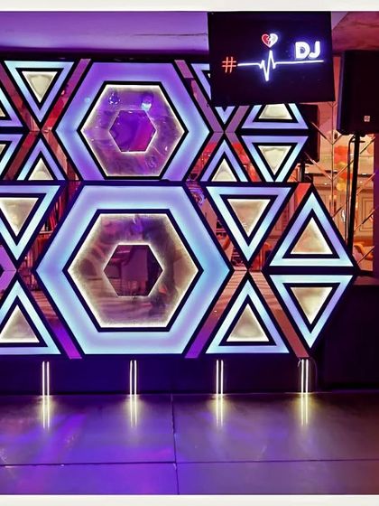 The DJ booth and stage setup for a birthday party. The geometric, illuminated backdrop adds a cool, modern vibe to the event.