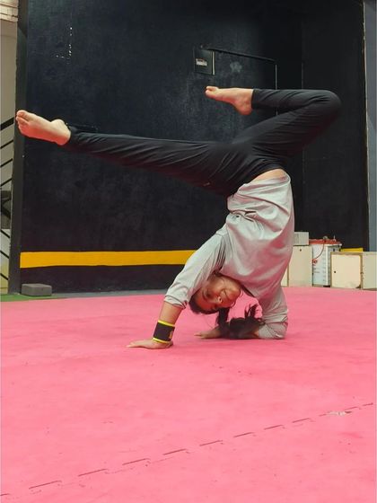 A student holds a scorpion pose in a forearm stand, showing off her amazing flexibility and balance.