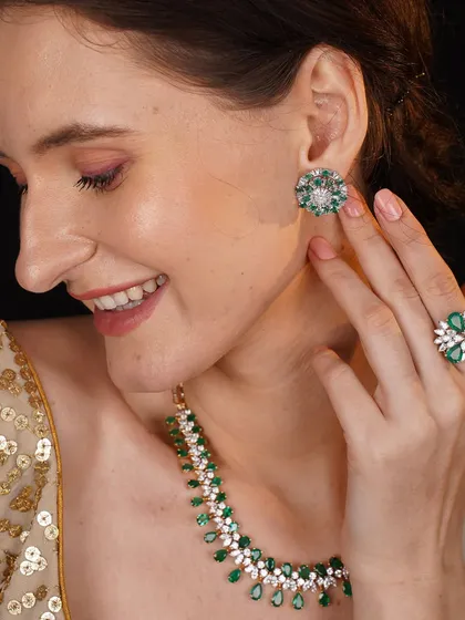 A model showcases a full parure of emerald and diamond jewellery, including a necklace, earrings, and ring.
