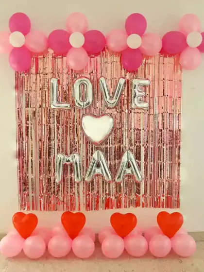 A 'Love Maa' decoration with a pink shimmer curtain and heart-shaped foil balloons.