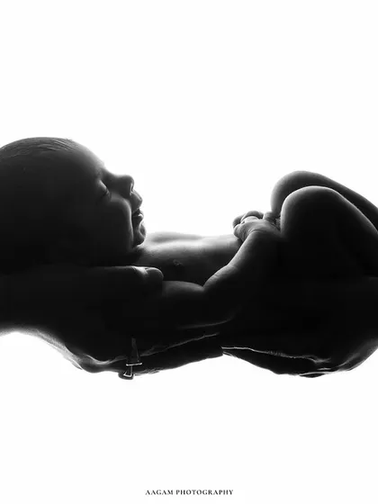A creative silhouette showing the baby held aloft in parental hands. This artistic shot symbolizes the hopes and dreams you hold for your child.
