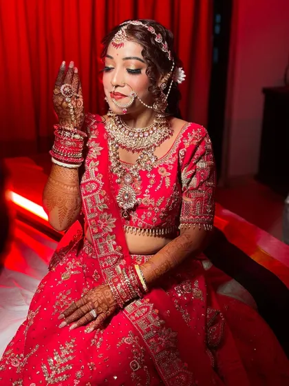 A candid moment of the bride, showcasing her dreamy red lehenga and the ethereal glow of her makeup. This look was a labor of love, designed to tell her unique story.