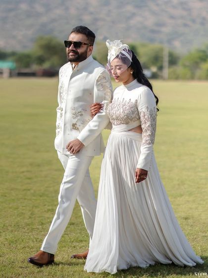 The couple walking across the polo field, a stylish and unconventional portrait from their destination wedding in Jaipur.
