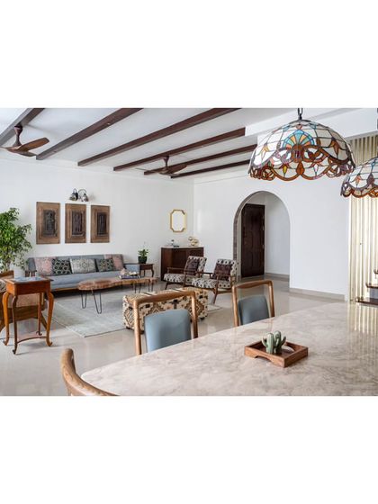 The open-plan living and dining area, unified by walnut-hued wooden rafters on the ceiling. This architectural element adds a vintage allure and conceals electrical wiring for a clean look.