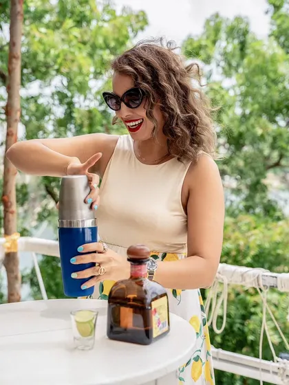 An expressive shot of a model shaking a cocktail at Olive Bistro. Her joyful expression and the action-oriented pose make the experience look fun and engaging.