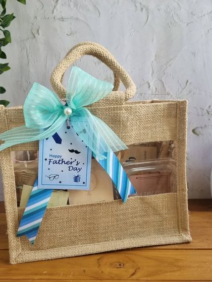 A Father's Day hamper in a jute bag with a clear window, showcasing the delicious treats inside.