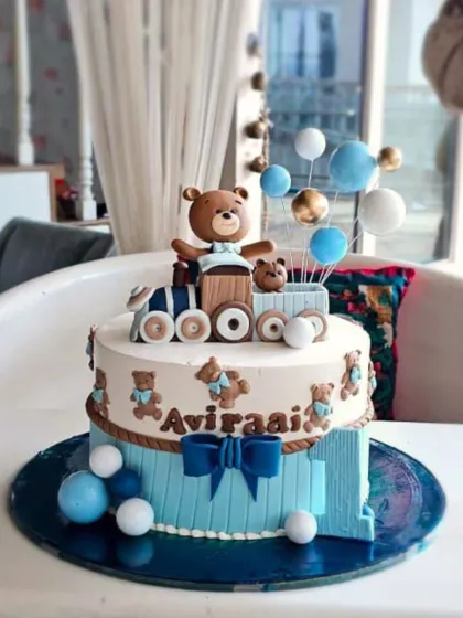 A delightful teddy bear train cake, with a cute bear conductor and balloon accents, perfect for a little one's special day.