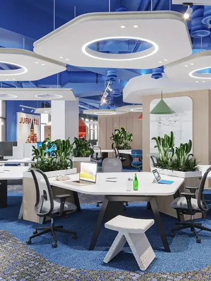 This is an example of a vibrant, open-plan office designed to foster collaboration. The hexagonal ceiling panels with integrated lighting, colorful accents, and strategically placed planters create an energetic and modern atmosphere.