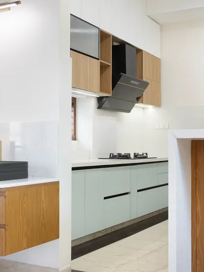 This shot shows the relationship between the kitchen and the separate wash area. The floating vanity with its modern black basin is framed by wood, echoing the kitchen's materials and creating a cohesive design story throughout the space.