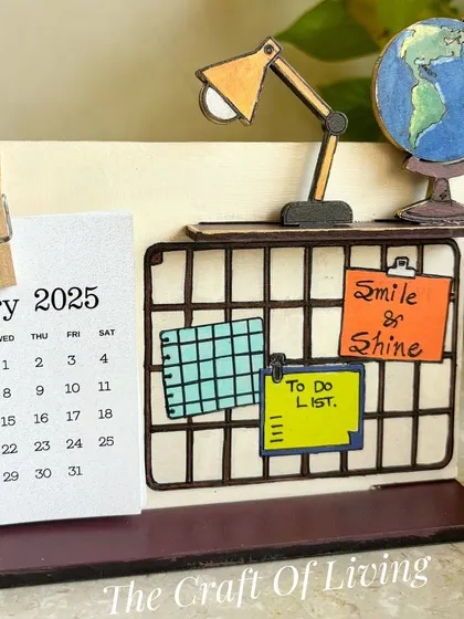 A closer look at the "Smile & Shine" desk calendar. The miniature desk, lamp, and globe add a whimsical and motivational touch to your workspace.