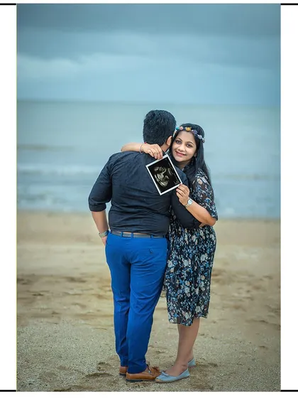 A sweet hug from behind on the beach, with the mom-to-be sharing the sonogram with the camera.