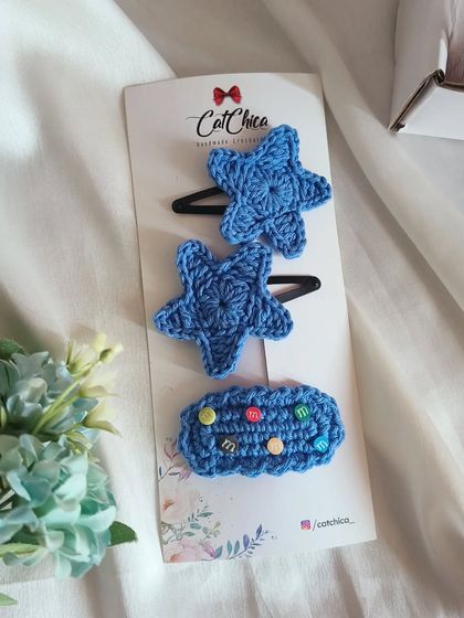 A fun set of blue-themed crochet clips, featuring two stars and a barrette decorated with colorful 'girly gems'.