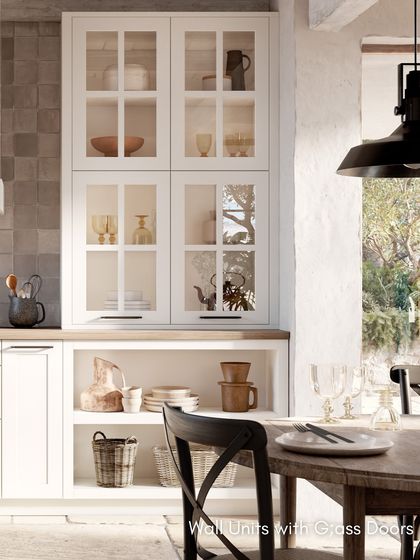 Wall units with glass doors in the RAVENNA White kitchen provide a beautiful display space for crockery, enhancing the modern country-style aesthetic.