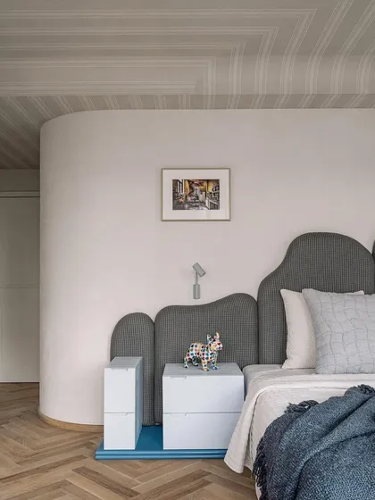 The master bedroom features a custom-designed, cloud-like headboard and playful, stacked bedside tables. The design is all about soft curves and tranquil vibes.