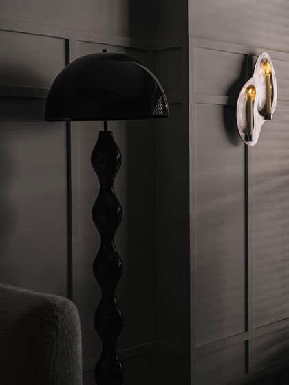 Details from Frenchie Haus. The moody lighting from the sculptural black floor lamp and the unique wall sconce creates an intimate and sophisticated atmosphere, perfect for unwinding.