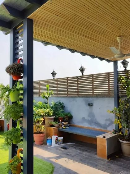 A simple and functional pergola with a bamboo ceiling, providing shade for a long seating area on this plant-filled terrace.