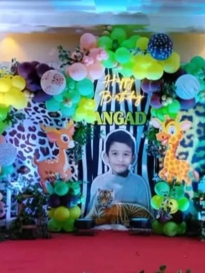 A full-scale jungle adventure for a 5th birthday. This stage decoration is filled with friendly animal cutouts like lions, tigers, and elephants, set against a lush backdrop with a personalized photo of the birthday boy to make him the king of the jungle.
