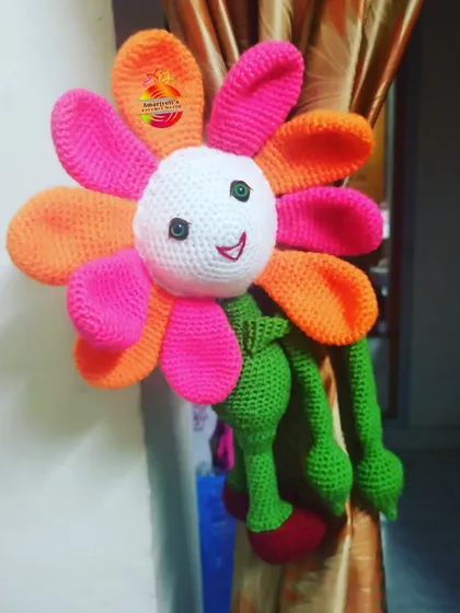 This is my flower doll curtain holder, a playful and unique way to tie back your curtains. The doll has bright, cheerful petals and long arms that wrap around the curtain, adding a touch of handmade charm to any room.