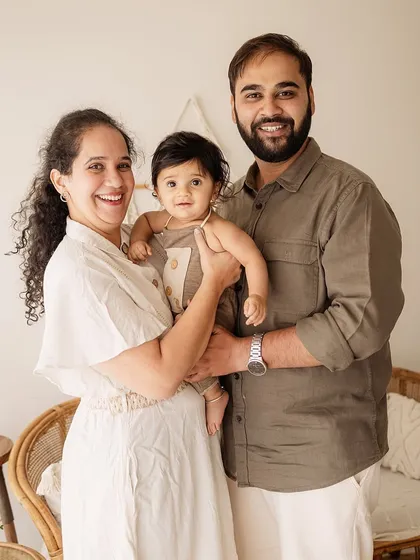 A happy family of three posing in a boho-inspired studio setup. The natural textures and earthy tones complement their joyful expressions.