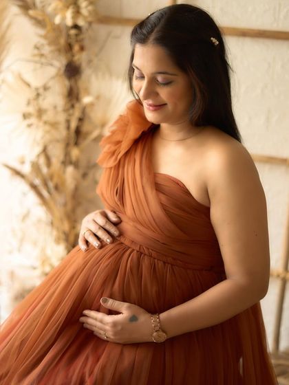A serene solo portrait in our Copper gown. The soft, natural light from the window creates a gentle and peaceful mood.