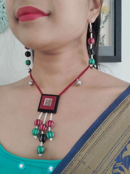 This beaded necklace set with a fabric pendant is perfect for both Navratri and other festive events. The combination of red, green, and black beads with small ghungroos adds a playful touch to any outfit.