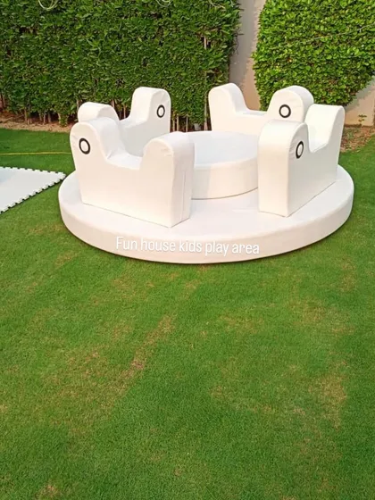The same white soft merry-go-round shown in an outdoor garden setting, demonstrating its versatility for both indoor and outdoor use.
