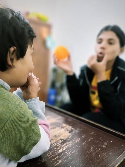 Here, a therapist uses a ball and mirror feedback to work on oral motor exercises. These activities are designed to strengthen the muscles of the lips, tongue, and jaw needed for clear speech.
