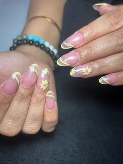 A delicate and pretty design with a nude base, sheer yellow French tips, and small, hand-painted yellow flowers.