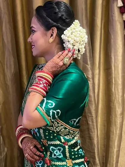 A side profile of a wedding guest looking elegant and ready for the event. I styled her hair in a classic bun and adorned it with a fresh white gajra for a timeless, traditional touch.