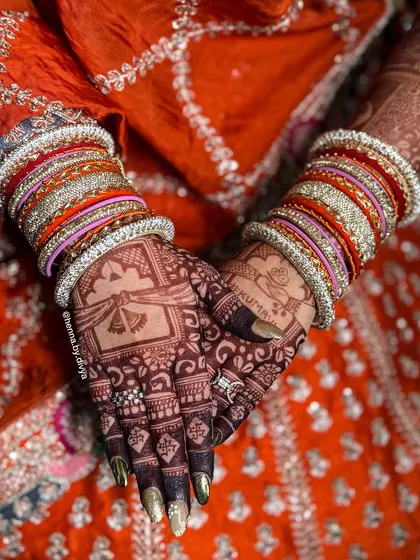 The back of the hands after the henna has stained. The deep color looks stunning against the bride's colorful bangles and traditional attire.