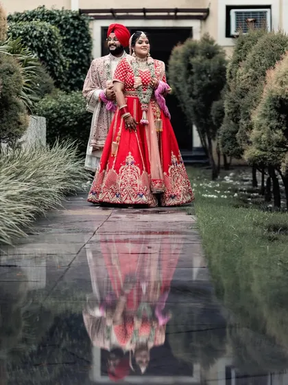 A creative couple portrait of a Sikh bride and groom, using a water reflection to create a stunning, symmetrical composition. This image demonstrates my eye for artistic shots that add a unique and memorable touch to a wedding album, capturing beauty in unexpected ways.