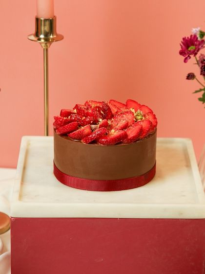 Our Chocolate Strawberry Gateau, a beloved classic, beautifully presented on a marble and wood cake stand.